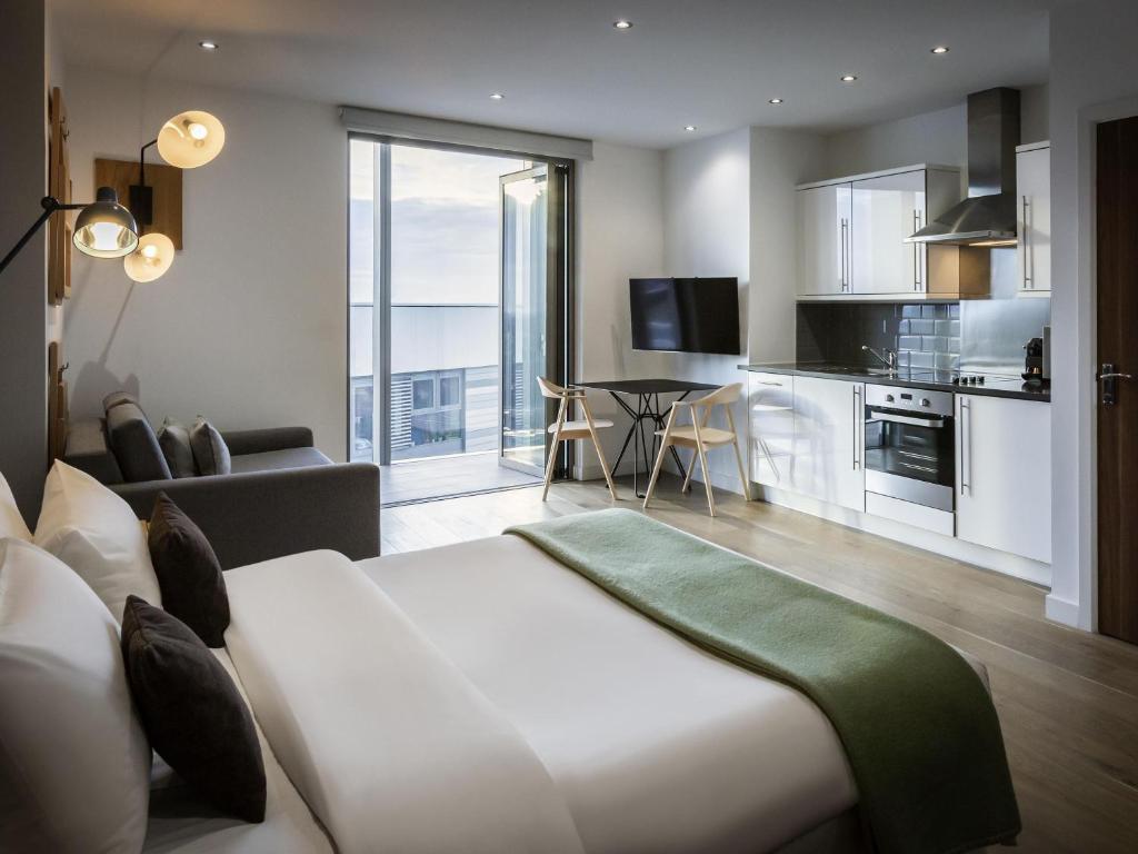 a living room with a large bed and a kitchen at Aparthotel Adagio London Brentford in Brentford