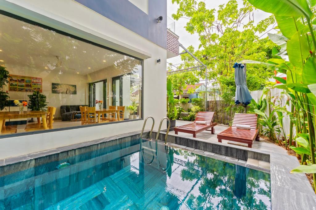 a swimming pool with two chairs next to a house at Buddy January Villa in Hoi An