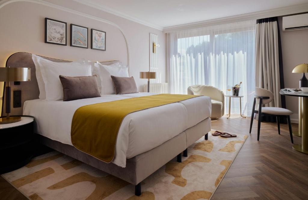 a bedroom with a large bed and a large window at Badischer Hof Baden-Baden - Leonardo Limited Edition in Baden-Baden