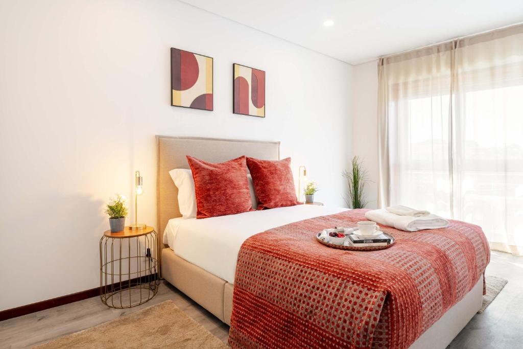 a bedroom with a large bed with red pillows at Bright & Spacious Flat with Balcony by HostWise in São Mamede de Infesta