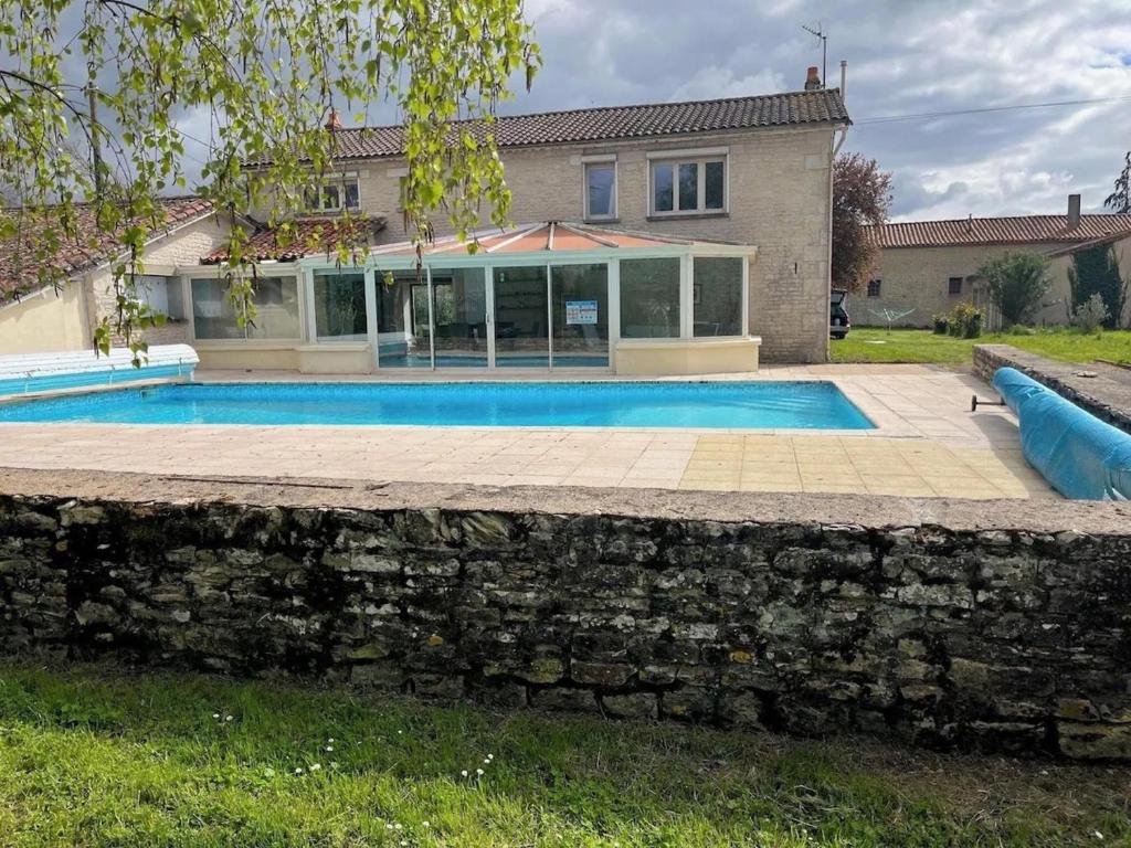 a house with a swimming pool and a stone wall at Sleeps10-PrivatePool-GamesRoom-GatedGardens in Paizay-le-Chapt