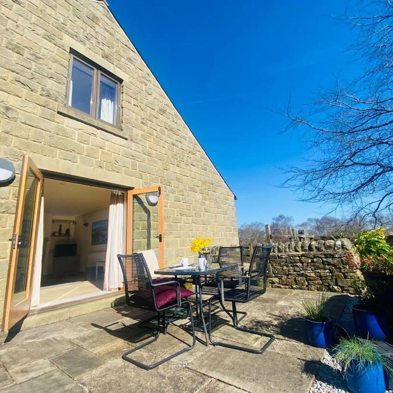a patio with a table and chairs in front of a building at Hollow Brook grown ups escape peace and quiet in Eyam