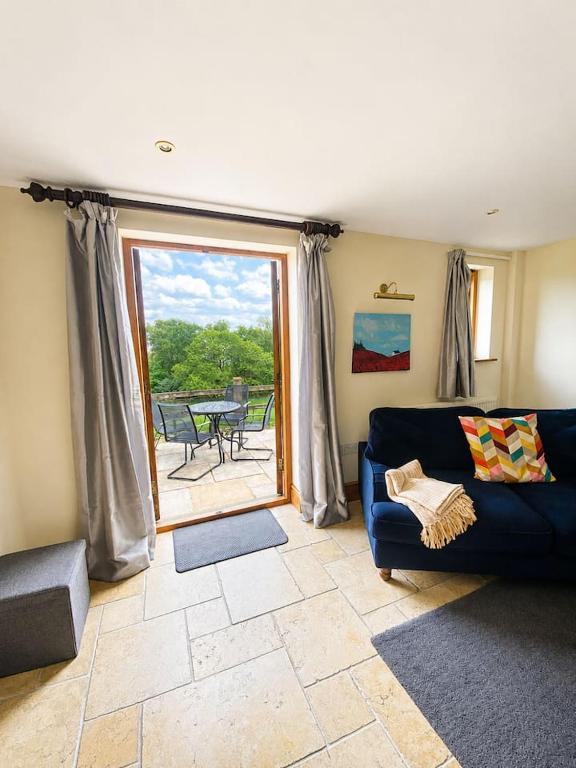 a living room with a blue couch and a patio at Pretty Wood Cottage Quiet Cottage in Private Meadow in Eyam