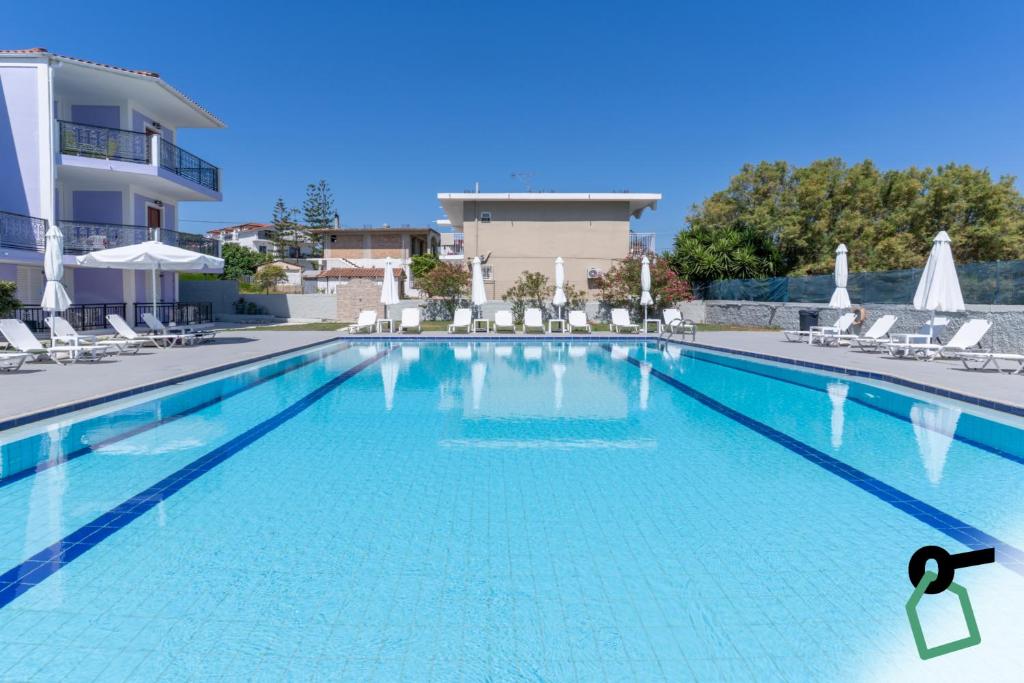 a large swimming pool with chairs and a building at Hotiday Zakynthos Argassi in Zakynthos