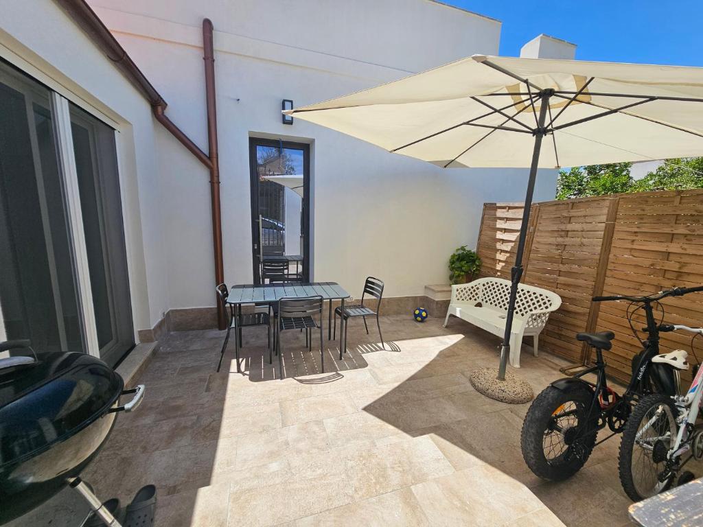a patio with an umbrella and a table and chairs at Teseo Holiday in Castelvetrano Selinunte