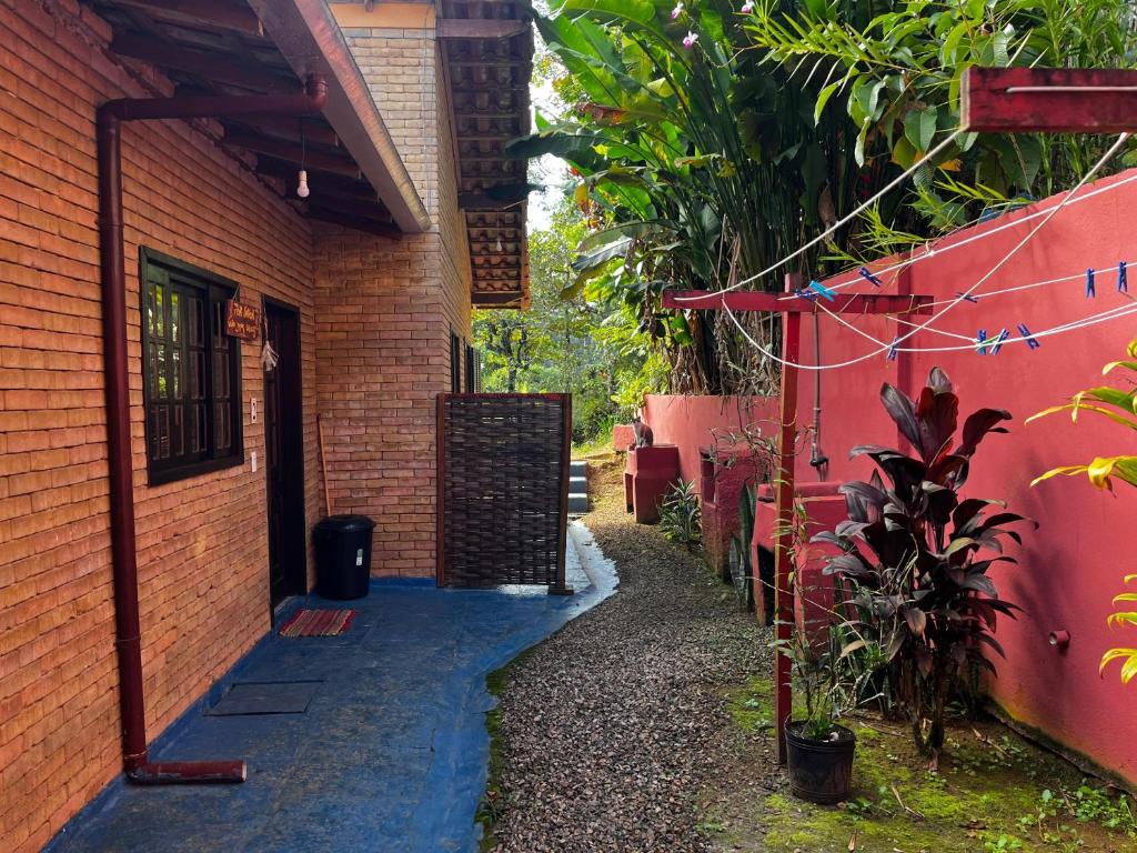 an alleyway leading to a building with a red wall at Tahoma Chalé Rustico Lila Prumirim in Ubatuba