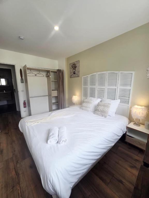 a large white bed with two towels on it at Chambre premium PLUME - jardin - 2p in Sainte-Geneviève-des-Bois