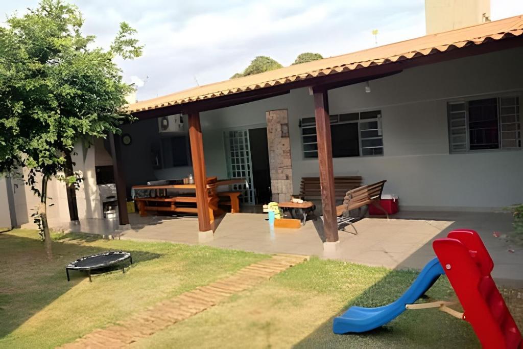 a backyard with a house with a slide and a playground at Dourados Guest Flat, your choice in Dourados-MS. in Dourados