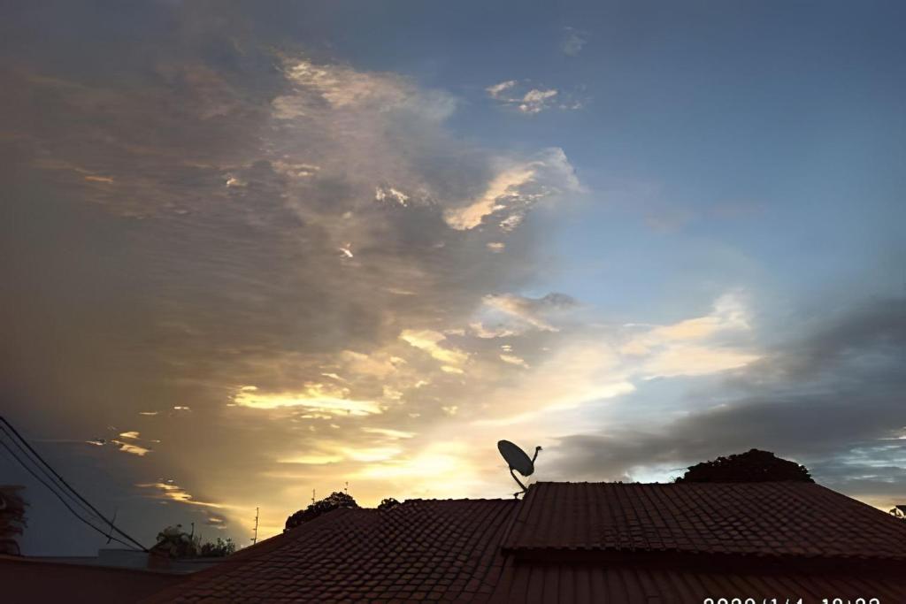 a bird on top of a roof with a cloudy sky at Dourados Guest Flat House in Dourados