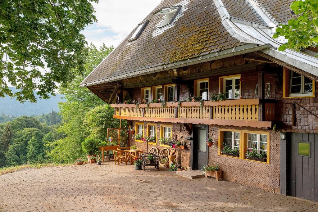 a large wooden house with a balcony and a table at Reesbauernhof - Fewo Abendrot in Oberried