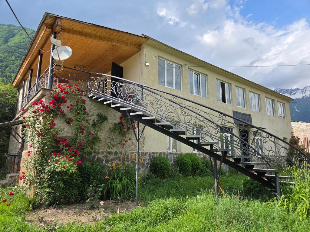 a house with a staircase in front of it with flowers at Babale's guesthouse in Mestia in Mestia