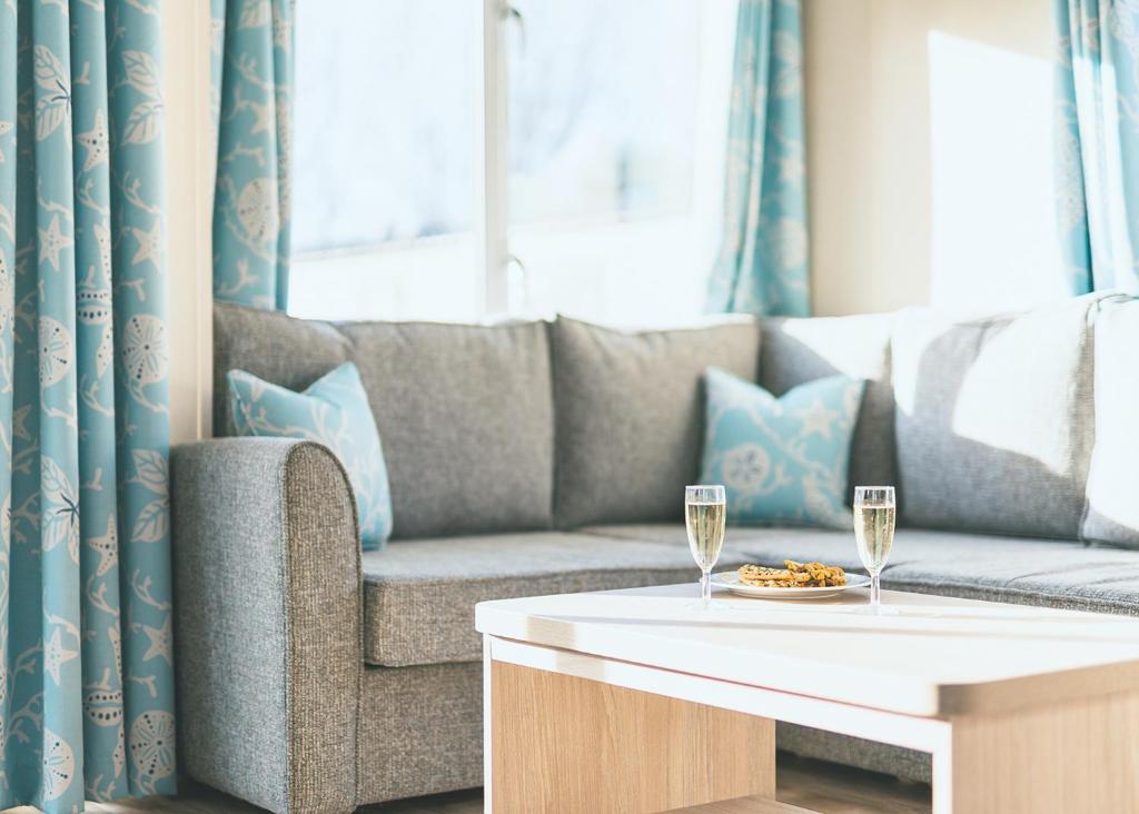 a living room with a couch and two glasses of wine at Talacre Beach Resort in Talacre