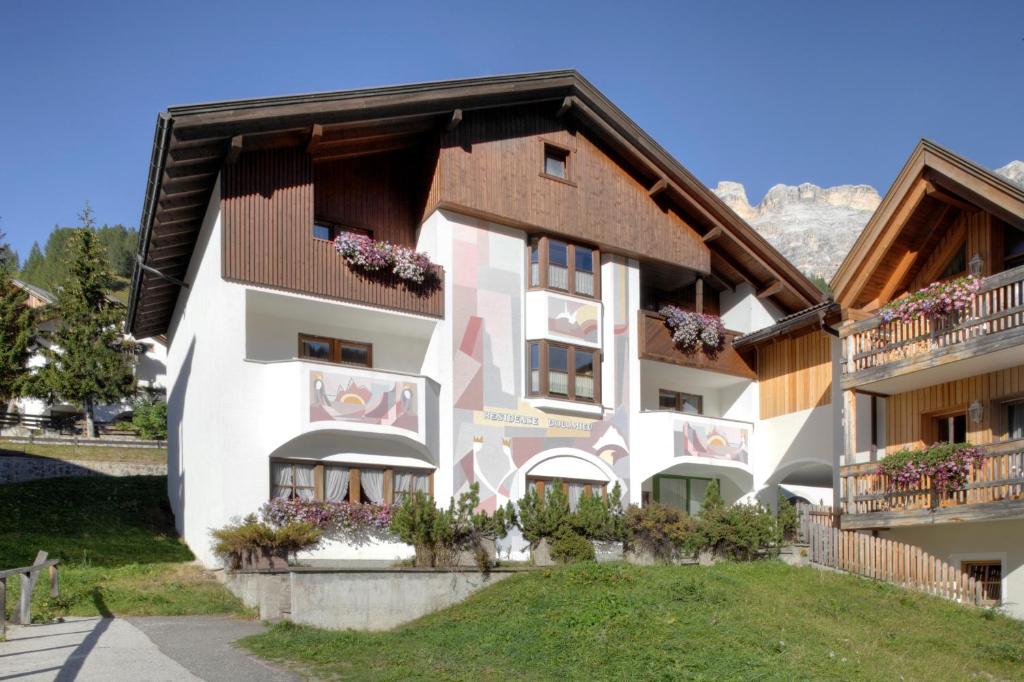 un edificio con balcones y flores. en Residence Dolomieu, en San Cassiano