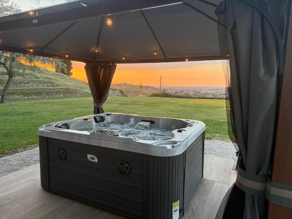 a hot tub under an umbrella on a patio at Le Essenze - Agriturismo con vista in Cesena