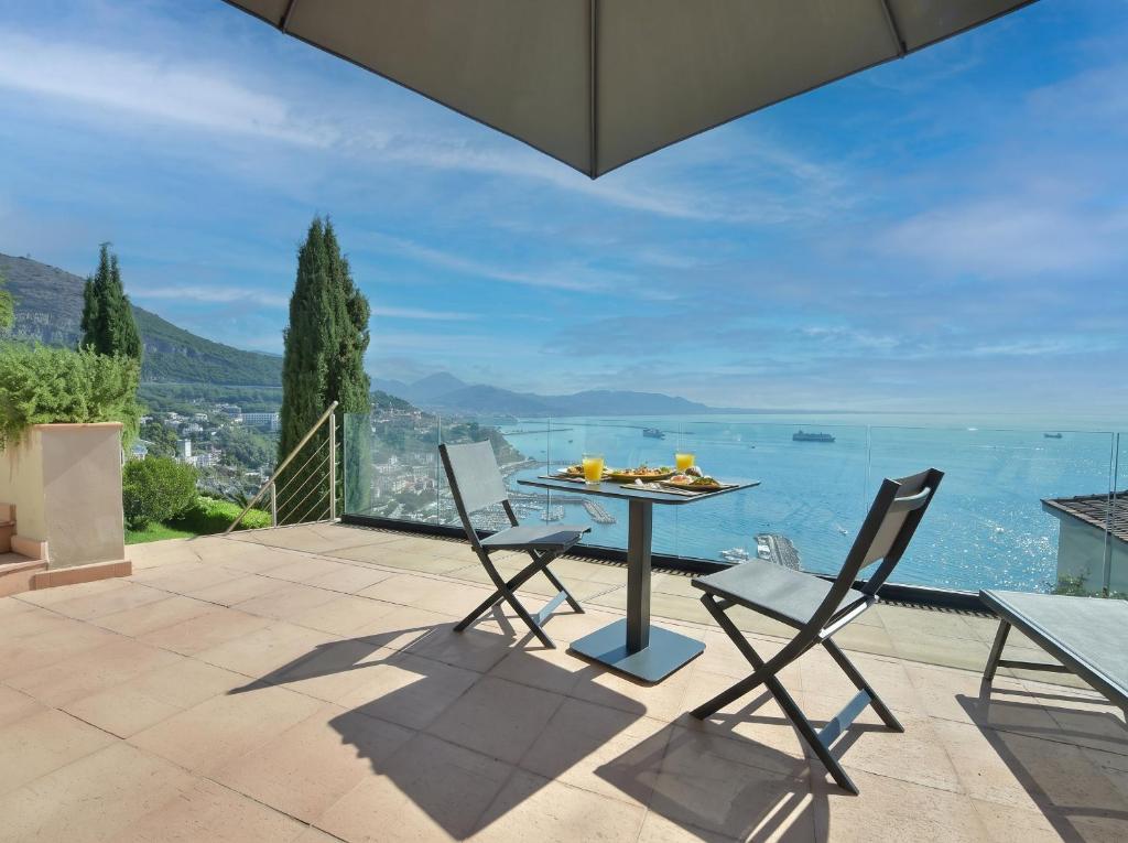 a patio with a table and chairs and the ocean at Mira Suite in Vietri sul Mare