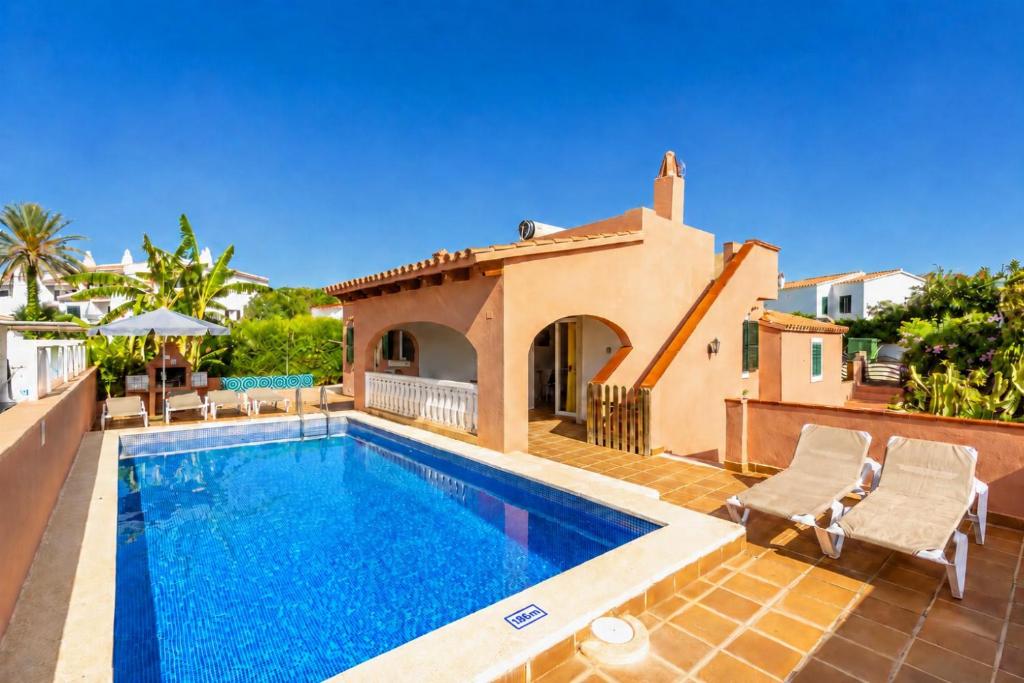 a villa with a swimming pool and a house at Villa Mares in Cala en Porter