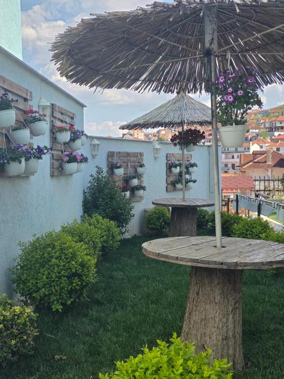 a wooden table with an umbrella in a yard at Vila Arbër 7 in Pogradec