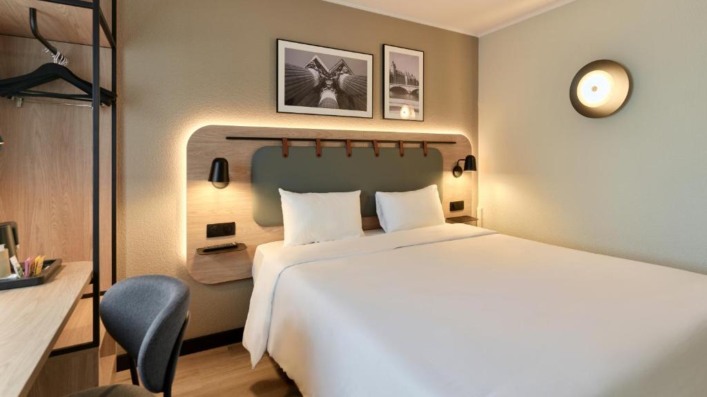 a hotel room with a large bed and a chair at Campanile PRIME - Paris - Porte de Bagnolet in Bagnolet