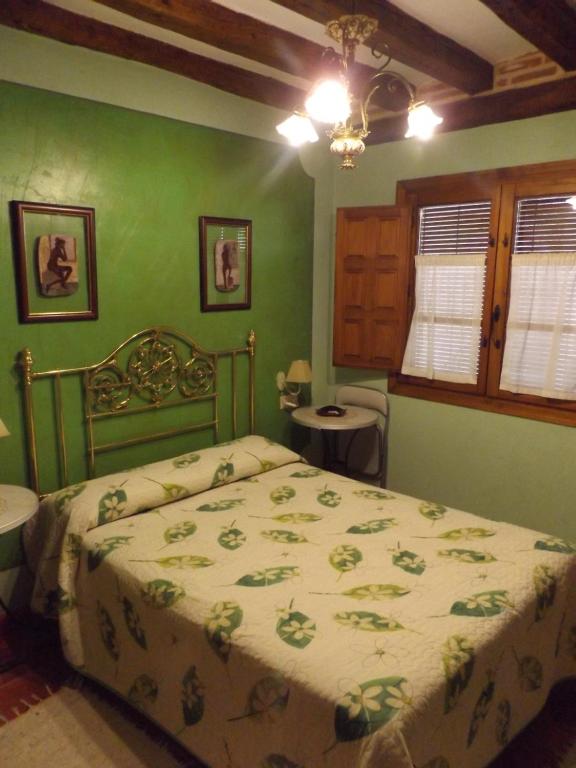 1 dormitorio con 1 cama en una habitación verde en La Fragua de los Alvaro, en Turégano