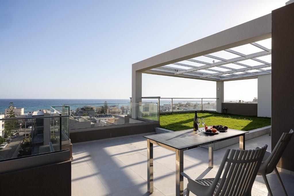 a balcony with a table and chairs and the ocean at Solianna Rethymno Suites in Rethymno