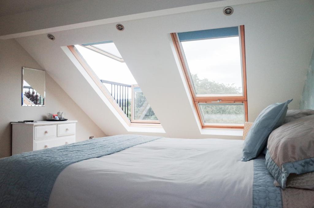 a bedroom with a large bed with two windows at Sophie's B&B in Birstwith