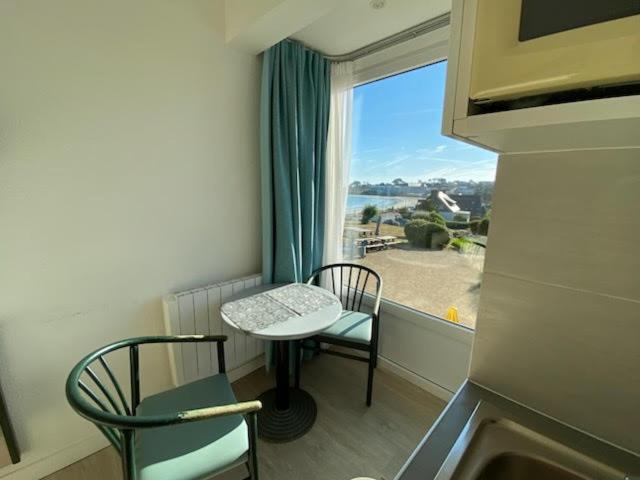 a room with a table and two chairs and a window at BELLE VUE MER STUDIO PISCINE in Trévou-Tréguignec