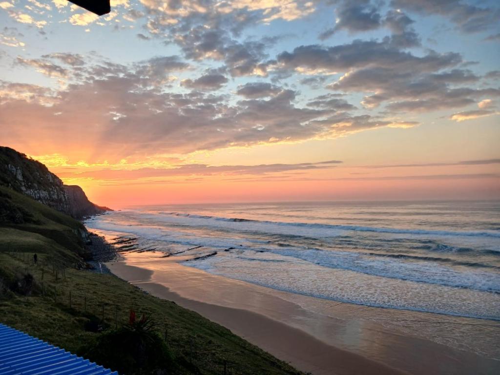 a sunset over a beach with the ocean at The Laughing Mermaid in Coffee Bay