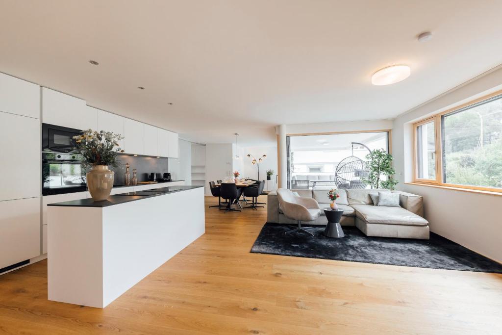 a kitchen and living room with a couch and a table at Bodensee Bergblick Nest by Stadtlandnest in Lochau