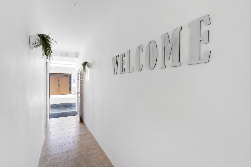Il corridoio d ingresso bianco con la scritta Welcome e le felci pendenti