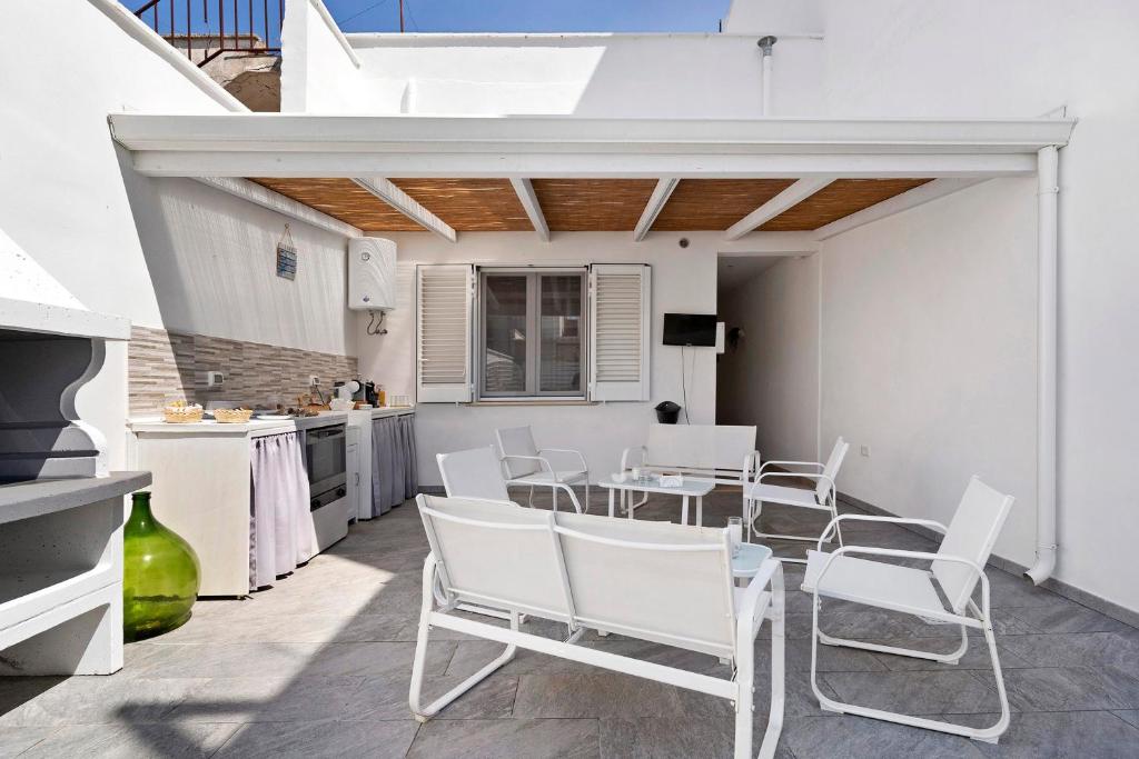 Il patio bianco di Notti in Salento con pergola in cannucciato, salotto e cucina esterna