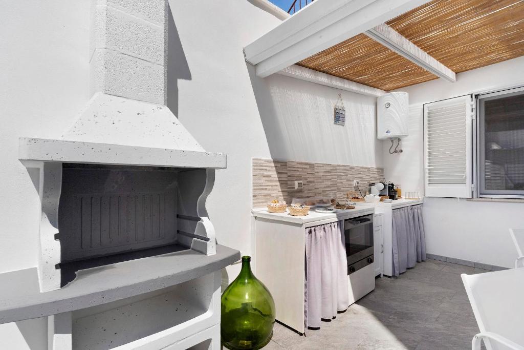 Barbecue in muratura bianca accanto alla cucina esterna sotto la pergola in cannucciato