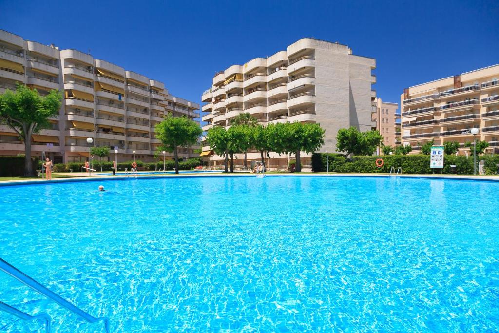 a large blue swimming pool with buildings in the background at UHC Jerez Cordoba Sevilla Apartments in Salou