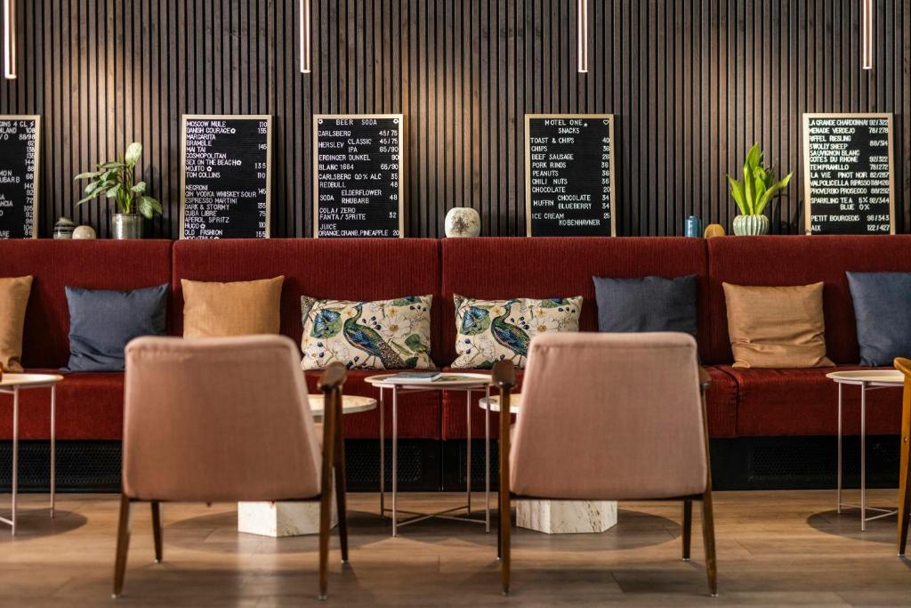a restaurant with a red couch and tables and chairs at Motel One Copenhagen in Copenhagen