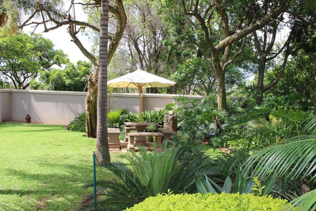 a garden with a table and an umbrella at Cashan BnB in Rustenburg