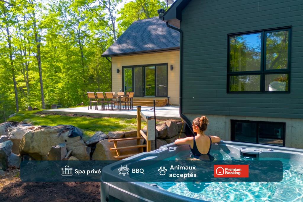 a woman in a hot tub in front of a house at Chalet Boréale with Private Spa & Billiards, Golf & Carling Lake in Brownsburg