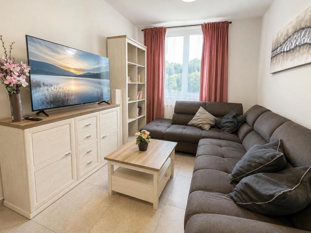 a living room with a couch and a flat screen tv at Aparthotel Olympland in Trutnov