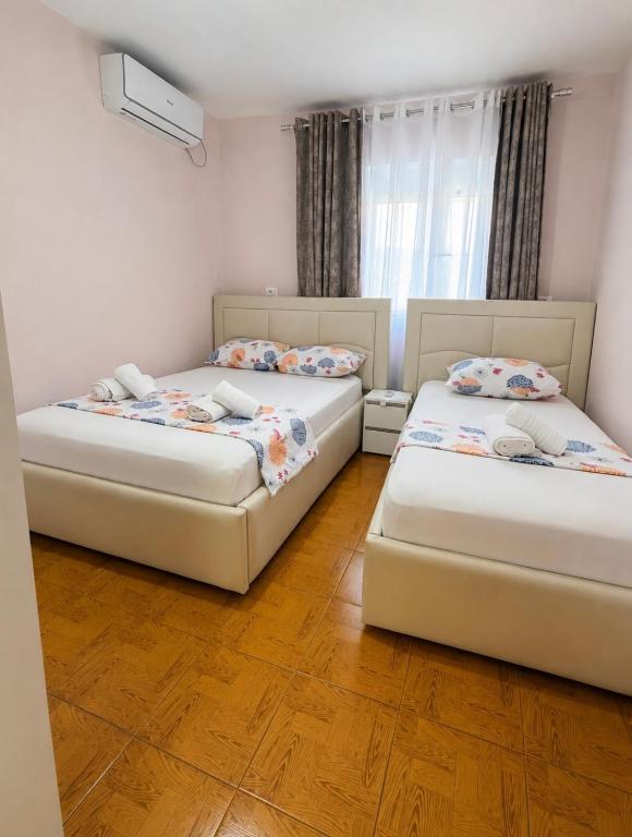 two beds in a room with wooden floors at Borsh Beach Apartment in Borsh