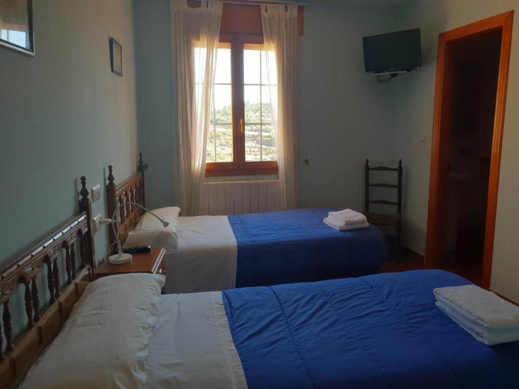 a hotel room with two beds and a television at Casa rural Casa Camilo in Agüero