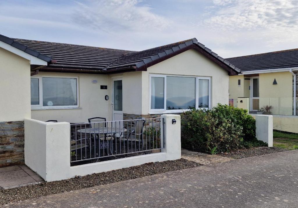 a house with a gate with a table in it at Widdy Bay View in Widemouth Bay