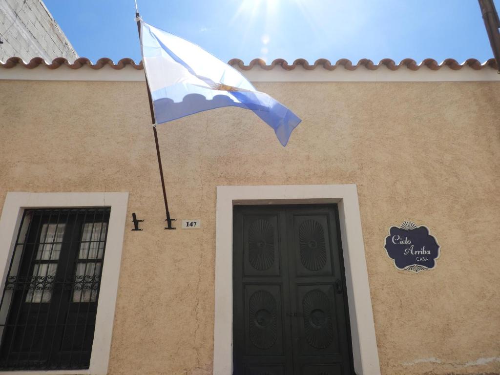 una bandera ondeando frente a un edificio con puerta en Cielo Arriba Casa en Humahuaca