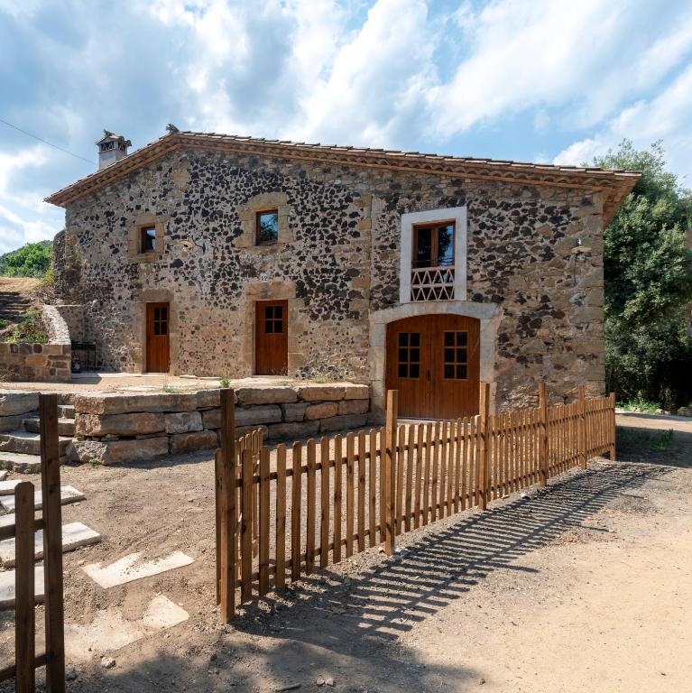 an old stone building with a wooden fence at Can Quel in Canet de Adri