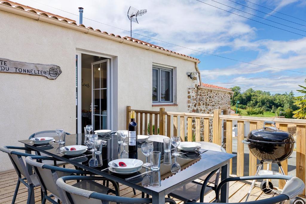 a table and chairs on a deck with a house at Gîte Du Tonnelier - 7min Puy du Fou in Sevremont