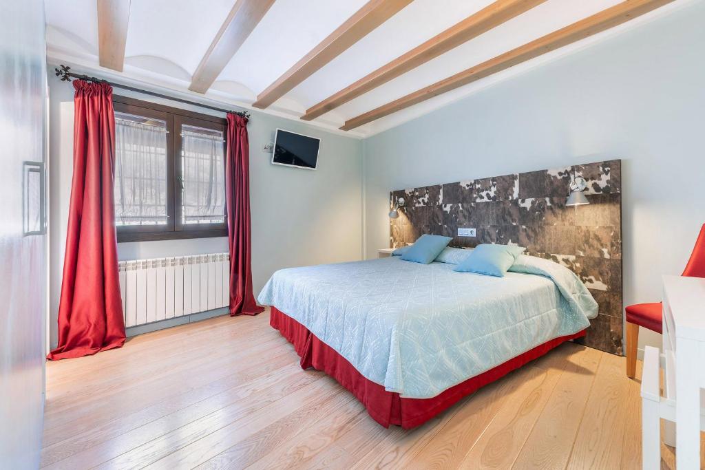 a bedroom with a large bed with red curtains at OTTIUM Albanuracín in Albarracín