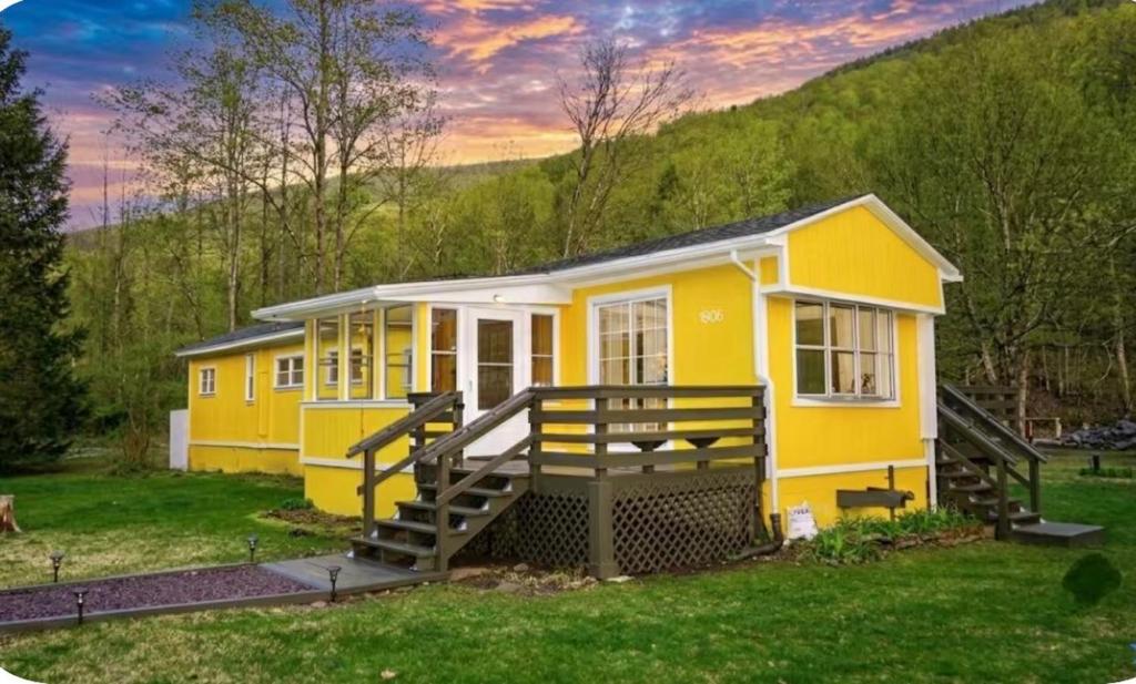 a yellow tiny house in the middle of a yard at Nemandua Catskills: Hot Tub+Fire Pit+Pool Table+EV in Lanesville