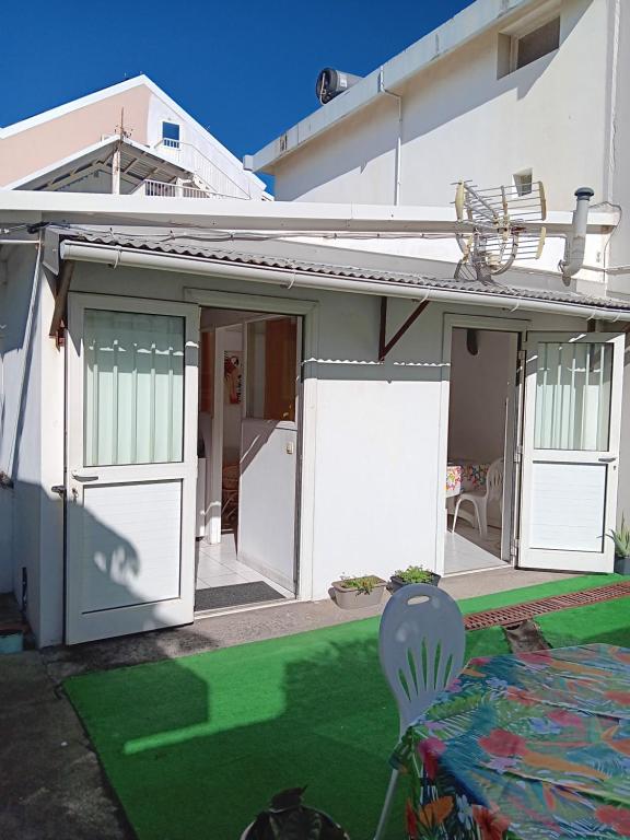 a house with white doors and a green yard at L'îlot vacances in Saint-Pierre