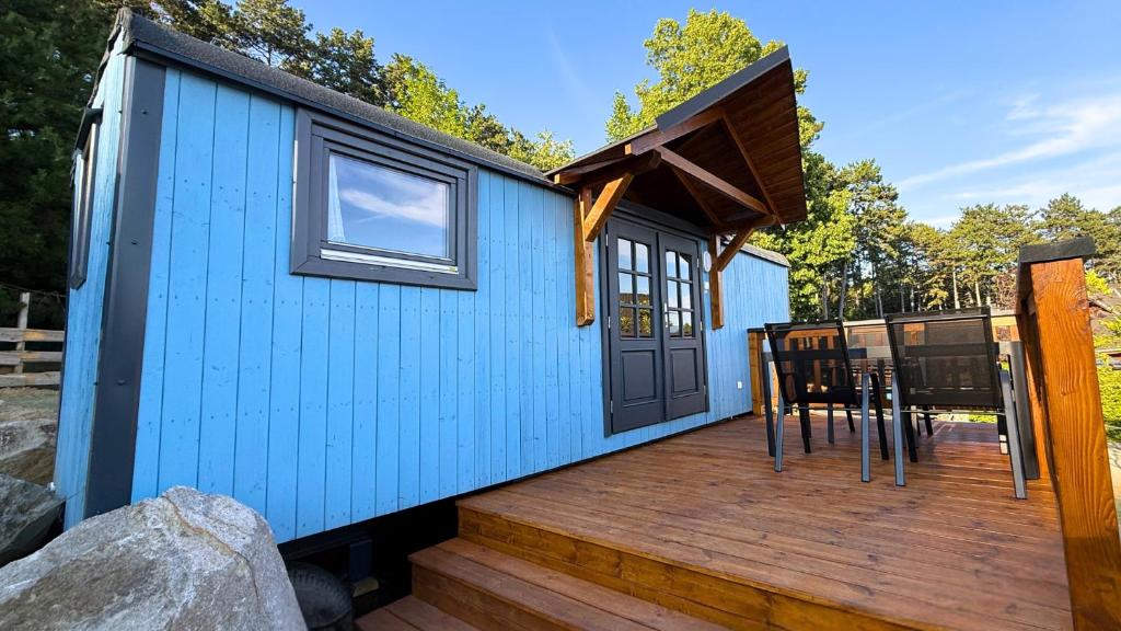 a blue tiny house with a wooden deck at Salaš Vígľaš in Bojnice