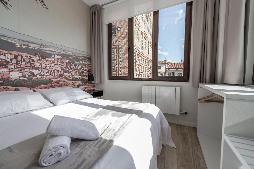 a bedroom with a white bed and a large window at La Torre Boutique Apartamentos in Teruel