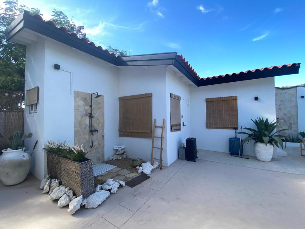 a white house with a ladder on the side of it at Palm Beach Vacay Suites - Garden Suite - Poolside in Palm-Eagle Beach