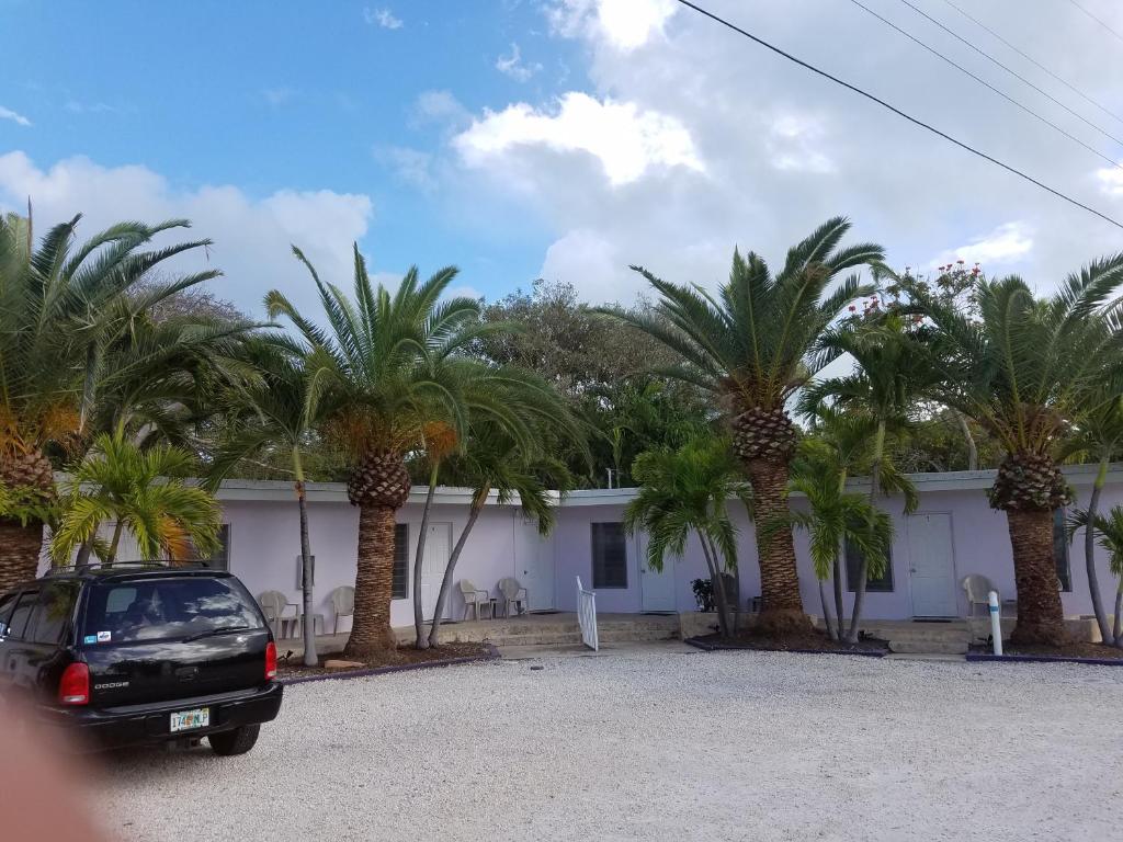 un coche aparcado frente a un edificio con palmeras en Siesta Motel en Marathon