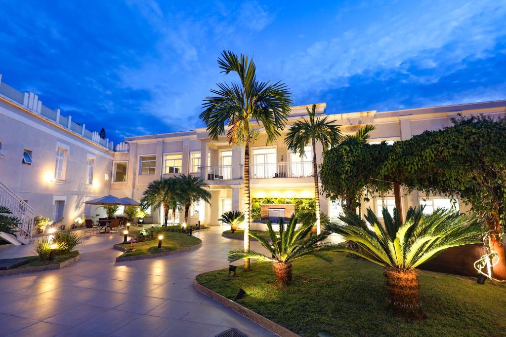 a hotel with palm trees in front of a building at Grande Hotel Águas da Prata in Águas da Prata